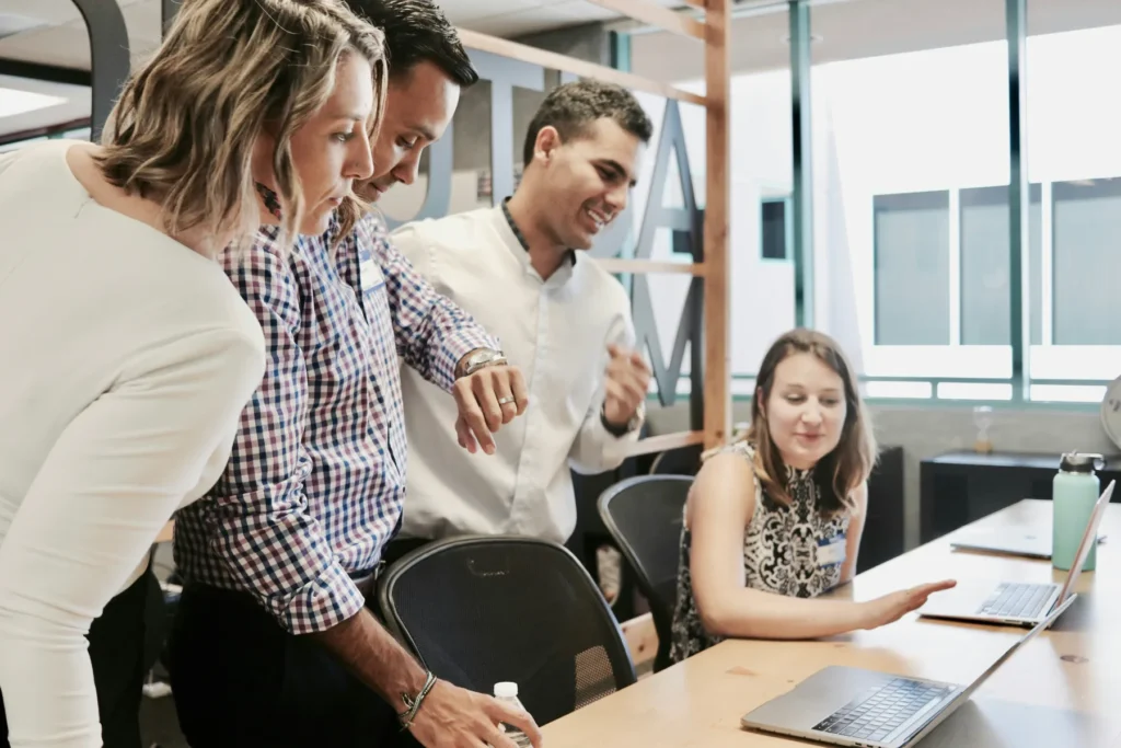 Employees meeting at desk with laptops